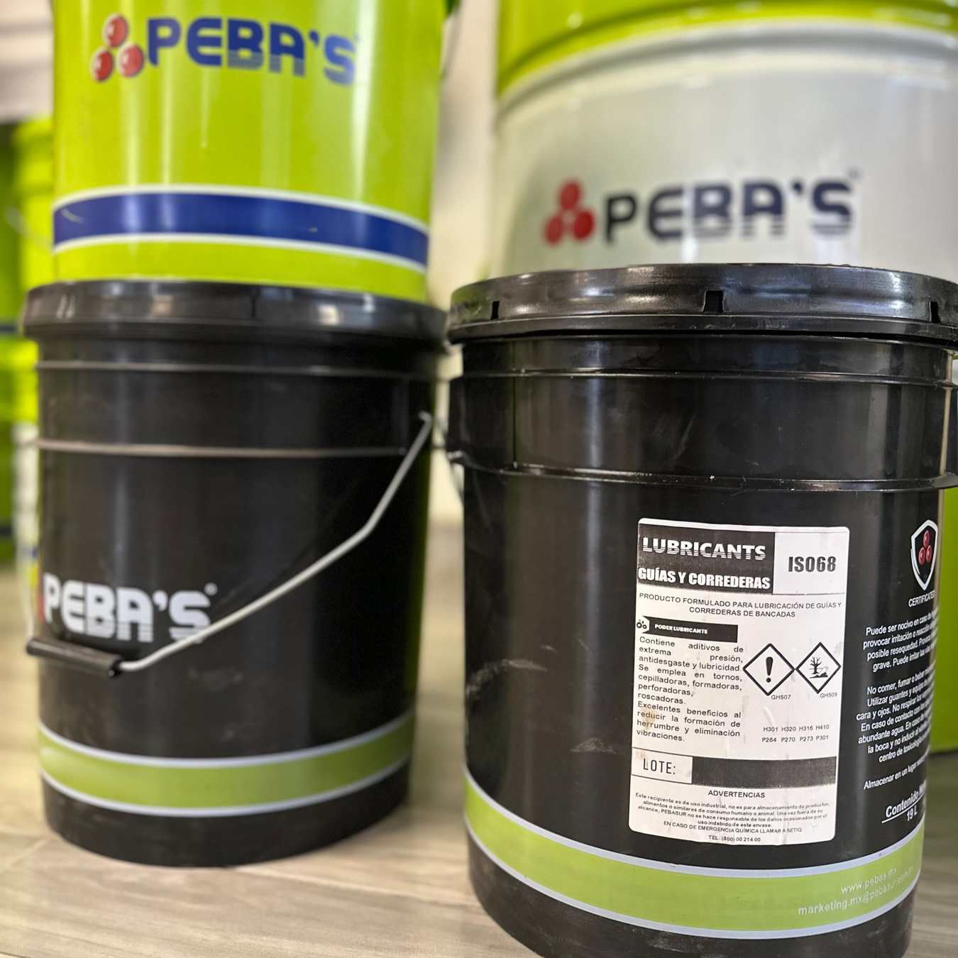 Primer plano: Cubetas negras de aceite marca Pebas
Segundo plano arriba: Cubeta y tambo verdes marca Pebas