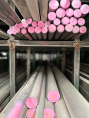 Fotografía de barras de acero pintadas color rosa en rack