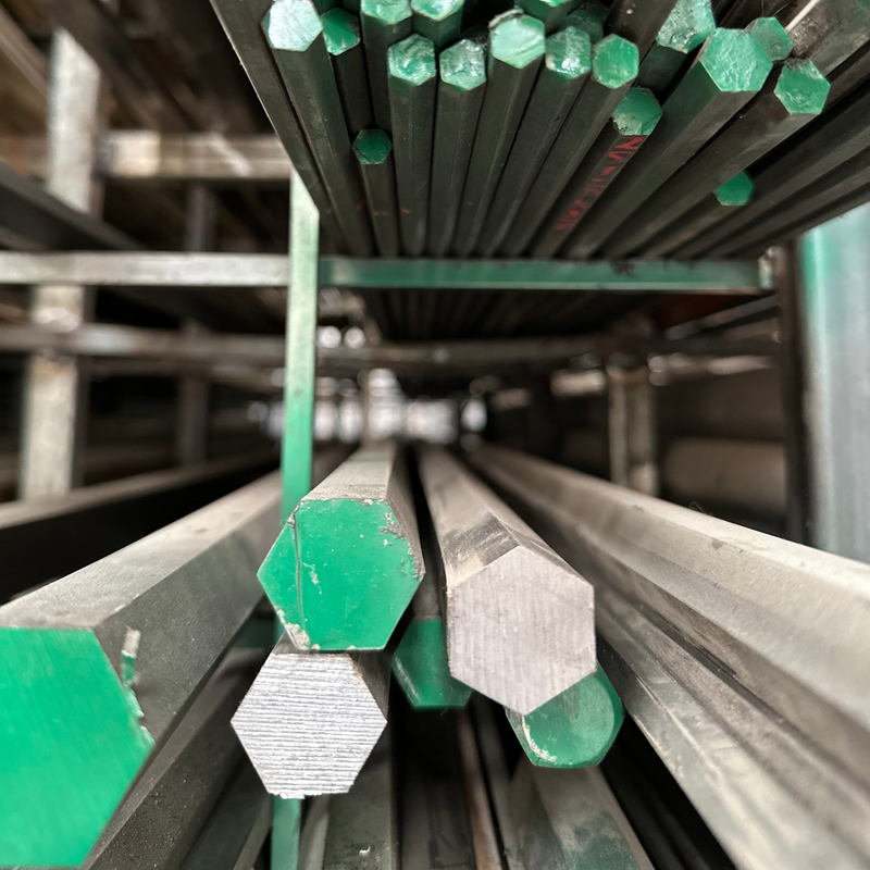 Perfiles hexagonales de acero 1018  pintados de verde acomodados en rack.