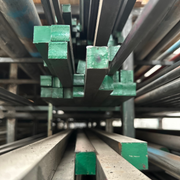 Fotografía de perfiles cuadrados de acero almacenados, pintados color verde.